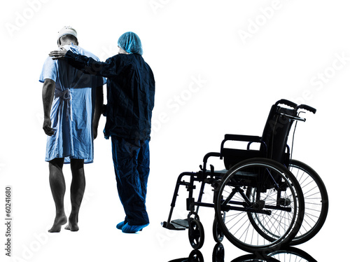 Photo: injured man walking away from wheelchair with nurse silhouette injured man walking away from wheelchair with nurse silhouette