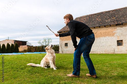 Photo: Young man playing with his dog in garden Young man playing with his dog in garden