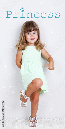 Photo: Little cute girl on carpet, on gray background Little cute girl on carpet, on gray background