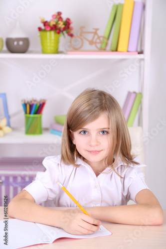 Photo: Little girl sitting at desk in room Little girl sitting at desk in room