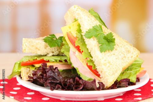 Photo: Fresh and tasty sandwiches on plate on table on light Fresh and tasty sandwiches on plate on table on light