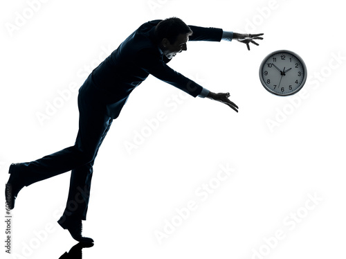 Photo: business man running after clock silhouette business man running after clock silhouette