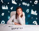 Young businesswoman sitting at desk with diagrams and statistics