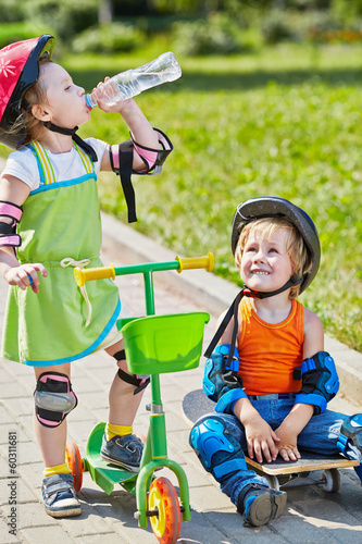 Photo: Little boy sits on skateboard and looks at little girl Little boy sits on skateboard and looks at little girl