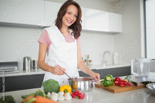 Photo: Portrait of smiling woman preparing food in kitchen Portrait of smiling woman preparing food in kitchen