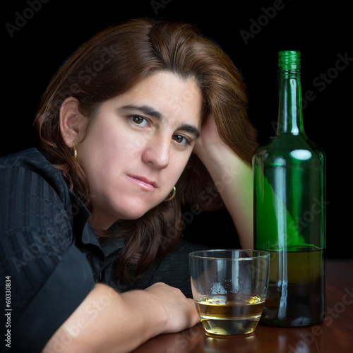 Photo: Portrait of a latin woman drinking alone isolated on black Portrait of a latin woman drinking alone isolated on black