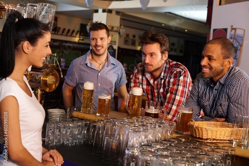 Photo: Young men flirting with bartender in pub Young men flirting with bartender in pub