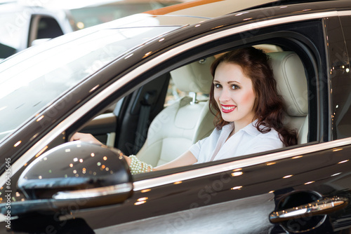 Photo: young woman in the new car in the showroom young woman in the new car in the showroom