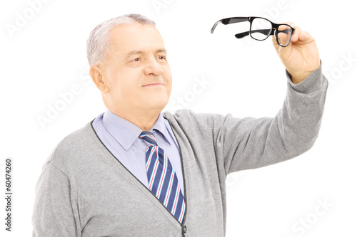 Photo: Senior gentleman holding a pair of glasses Senior gentleman holding a pair of glasses