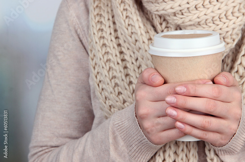 Photo: Hot drink in paper cup in hands on bright background Hot drink in paper cup in hands on bright background