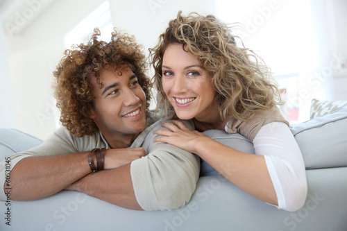 Photo: Sweet couple relaxing at home in sofa Sweet couple relaxing at home in sofa