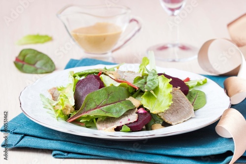 Photo: Fresh salad with lettuce leaves, boiled beef, beet, sauce Fresh salad with lettuce leaves, boiled beef, beet, sauce