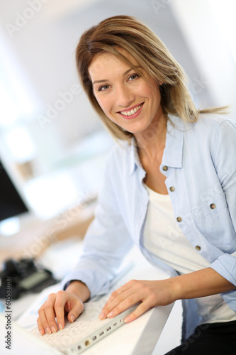 Photo: Smiling businesswoman working in office Smiling businesswoman working in office