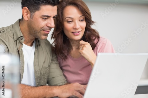 Photo: Couple using laptop in the kitchen Couple using laptop in the kitchen
