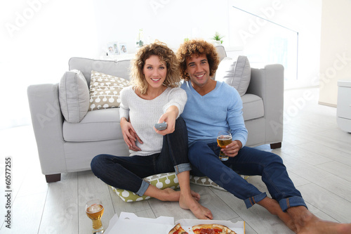 Photo: Cheerful couple at home having pizza in font of TV Cheerful couple at home having pizza in font of TV