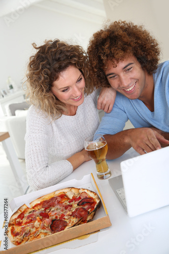 Photo: Couple eating pizza and websurfing on internet Couple eating pizza and websurfing on internet