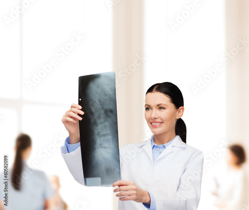 Photo: smiling female doctor looking at x-ray smiling female doctor looking at x-ray