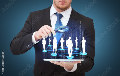 Photo: businessman hand holding magnifier over tablet pc businessman hand holding magnifier over tablet pc