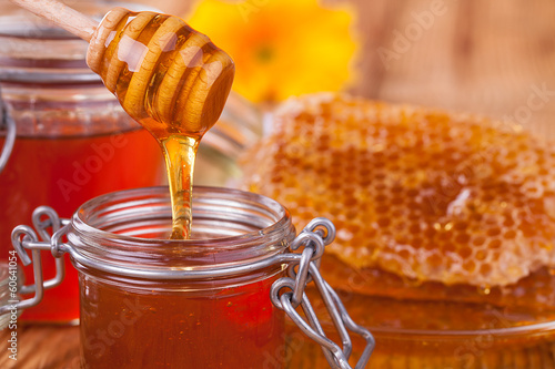 Photo: Honey in jar with honeycomb and wooden drizzler Honey in jar with honeycomb and wooden drizzler
