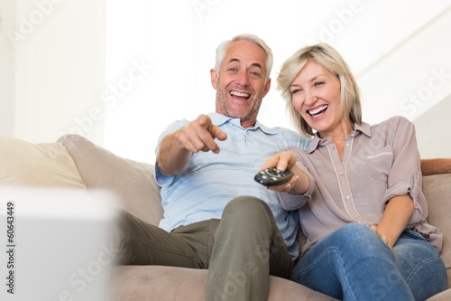 Photo: Cheerful couple watching tv at home Cheerful couple watching tv at home