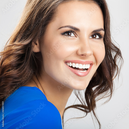 Photo: Happy smiling young woman, over grey Happy smiling young woman, over grey