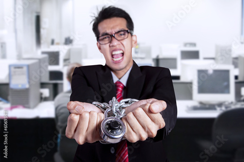 Photo: Angry businessman with hands chained at office Angry businessman with hands chained at office