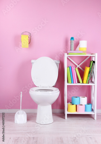 Photo: White toilet bowl and stand with books, on color wall White toilet bowl and stand with books, on color wall