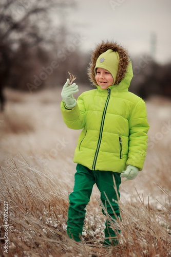 Photo: boy in a green suit walks in the park in winter with frozen tree boy in a green suit walks in the park in winter with frozen tree