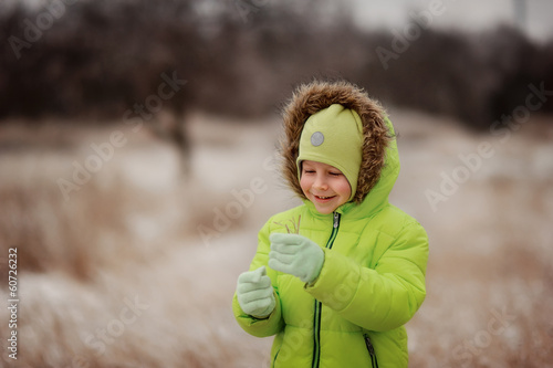 Photo: boy in a green suit walks in the park in winter with frozen tree boy in a green suit walks in the park in winter with frozen tree
