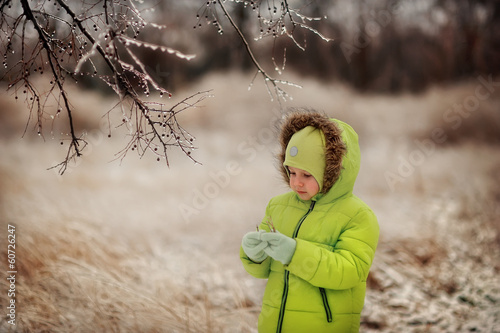 Photo: boy in a green suit walks in the park in winter with frozen tree boy in a green suit walks in the park in winter with frozen tree