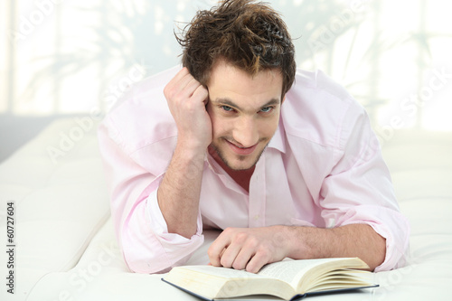 Photo: Man reading a book in bed Man reading a book in bed