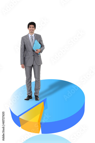 Photo: Businessman standing on a 3D pie chart Businessman standing on a 3D pie chart