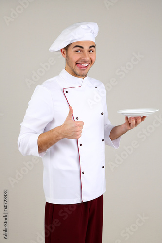 Photo: Professional chef in white uniform and hat, on gray background Professional chef in white uniform and hat, on gray background
