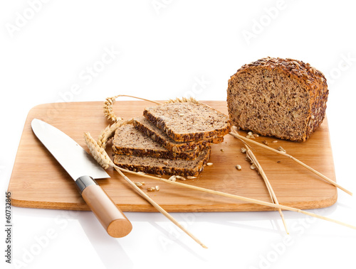 Photo: Fresh bread being sliced on a wooden cutting board with a bread Fresh bread being sliced on a wooden cutting board with a bread