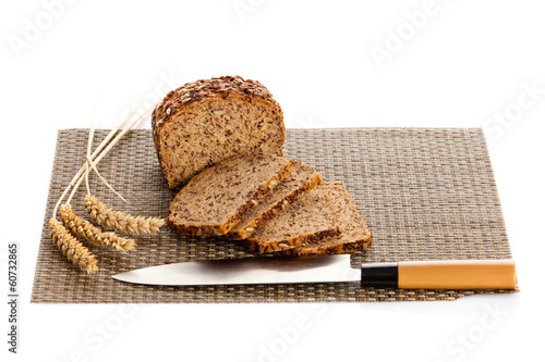 Photo: Fresh bread being sliced on a wooden cutting board with a bread Fresh bread being sliced on a wooden cutting board with a bread