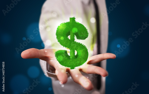 Photo: Young businessman presenting green glowing dollar sign Young businessman presenting green glowing dollar sign