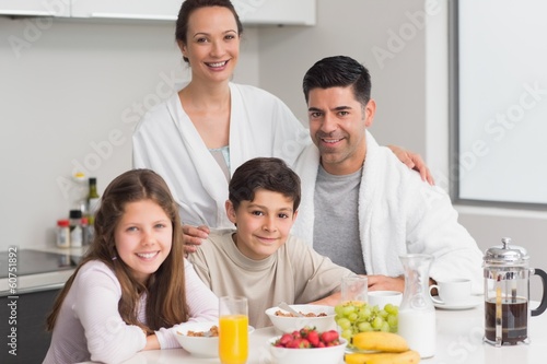 Photo: Portrait of happy kids enjoying breakfast with parents Portrait of happy kids enjoying breakfast with parents