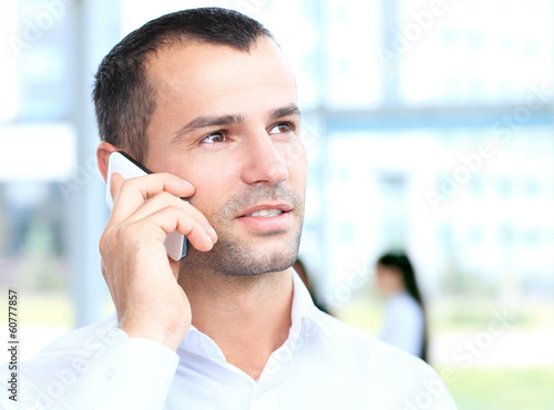 Photo: Businessman talking on the phone in office Businessman talking on the phone in office