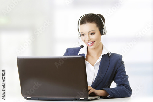 Photo: Beautiful young call-center assistant at the desk Beautiful young call-center assistant at the desk