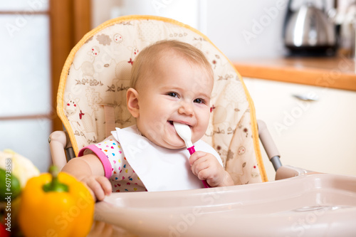 Photo: smiling baby girl eating food on kitchen smiling baby girl eating food on kitchen