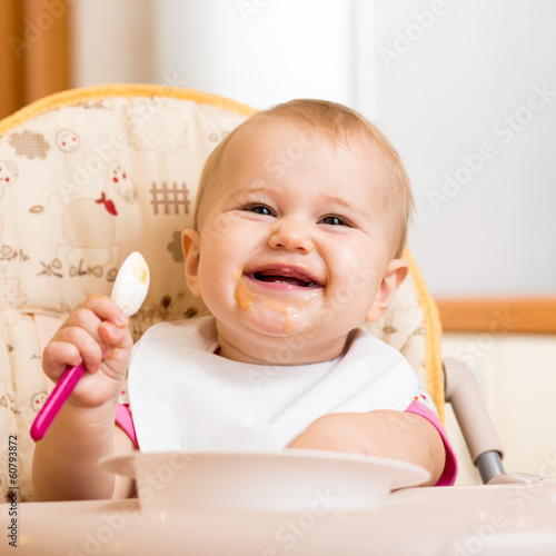 Photo: smiling baby eating food on kitchen smiling baby eating food on kitchen