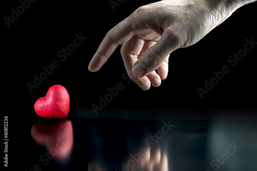 Photo: Man pointing to a red heart Man pointing to a red heart