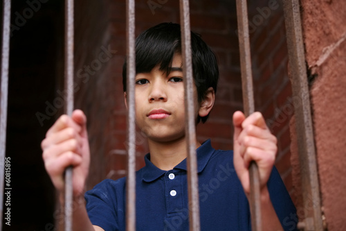 Photo: Boy standing behind bars Boy standing behind bars