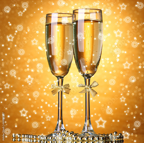 Photo: Two glasses of champagne on bright background with lights Two glasses of champagne on bright background with lights