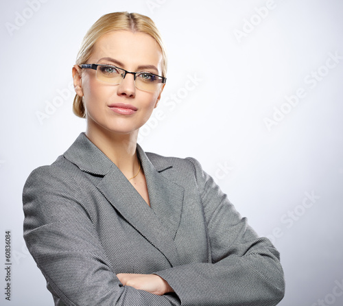 Photo: Portrait of a beautiful young business woman standing against gr Portrait of a beautiful young business woman standing against gr