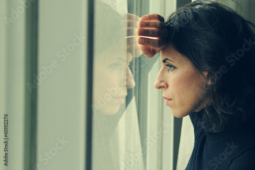 Photo: beautiful 35 year old woman stands in front of the window beautiful 35 year old woman stands in front of the window