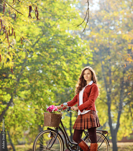 Photo: Beautiful female posing in a park with her bicycle Beautiful female posing in a park with her bicycle