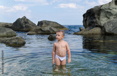 Photo: Small boy paddling in a tidal pool at the seaside Small boy paddling in a tidal pool at the seaside