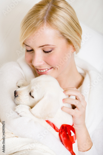 Photo: Woman holding white Labrador puppy with red ribbon on the neck Woman holding white Labrador puppy with red ribbon on the neck