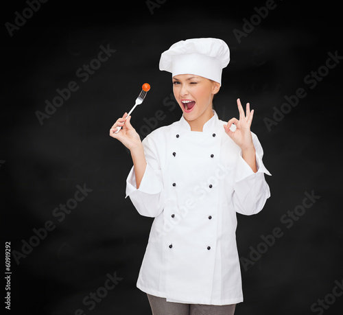 Photo: smiling female chef with fork and tomato smiling female chef with fork and tomato